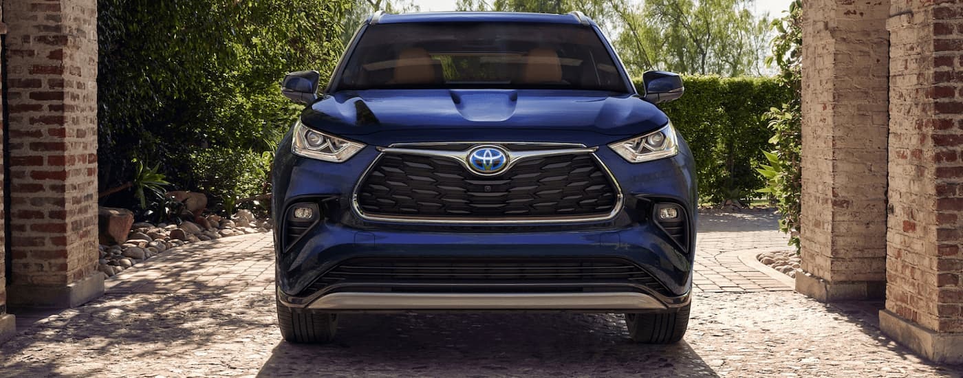 A blue used 2022 Toyota Highlander Hybrid Platinum for sale is shown from the front parked on a brick driveway.