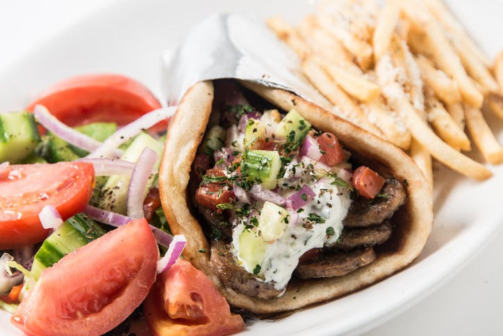 Gyro pita sandwich with middle eastern fries and salad close up