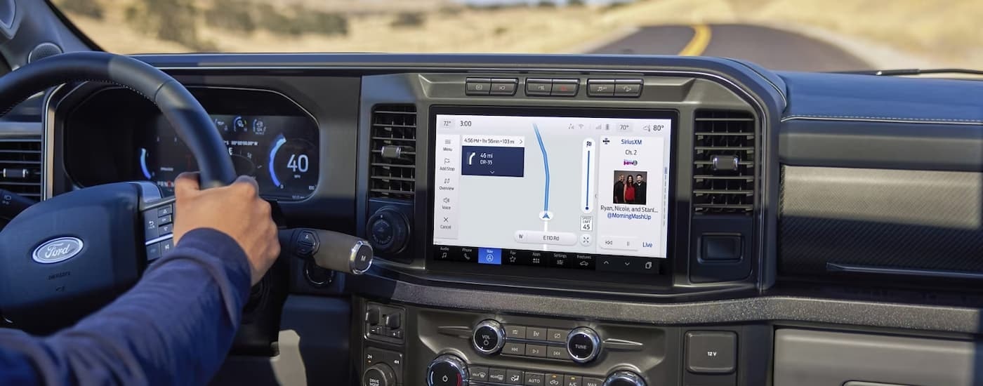 The infotainment screen in a 2023 Ford F-250 shows the GPS screen while driving on an open road.