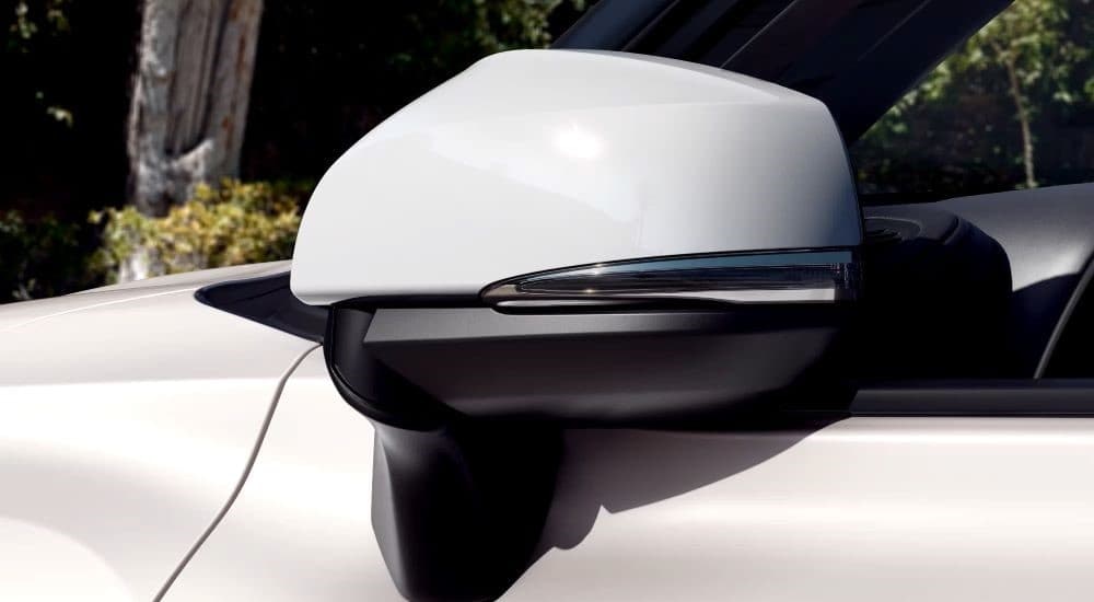 A close up of the side mirror on a white 2023 Toyota Highlander Platinum is shown.