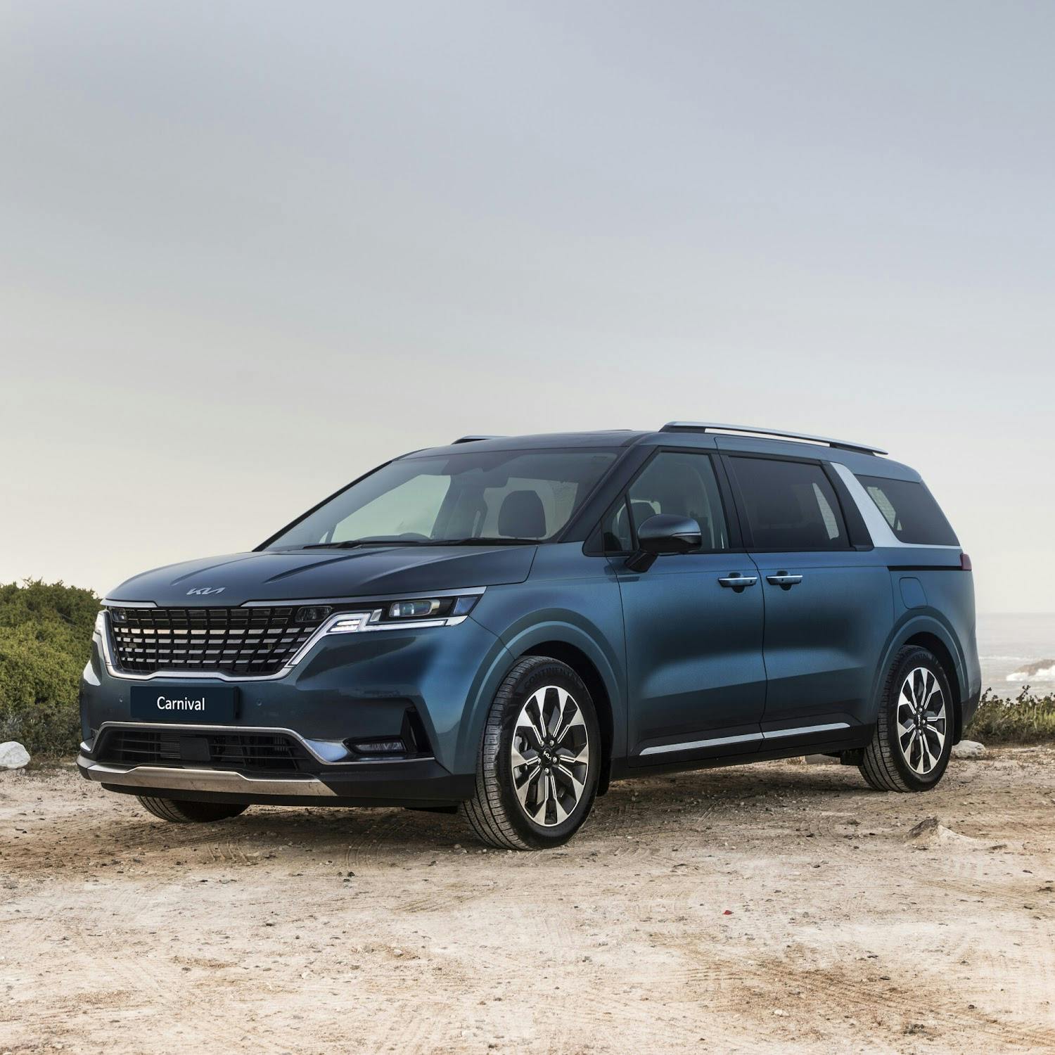 blue kia carnival on a rocky pavement