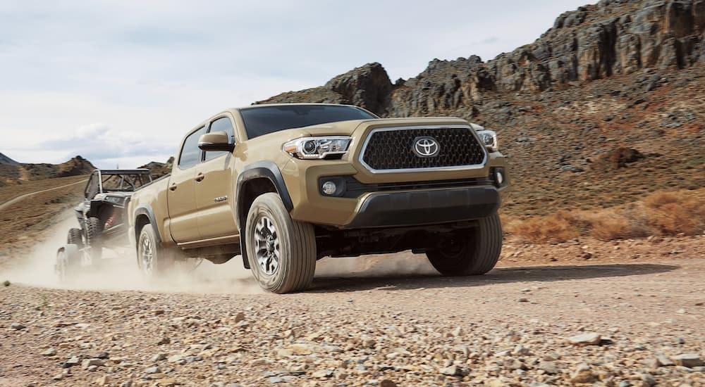 A tan 2019 Toyota Tacoma is shown off-roading on a rocky road.