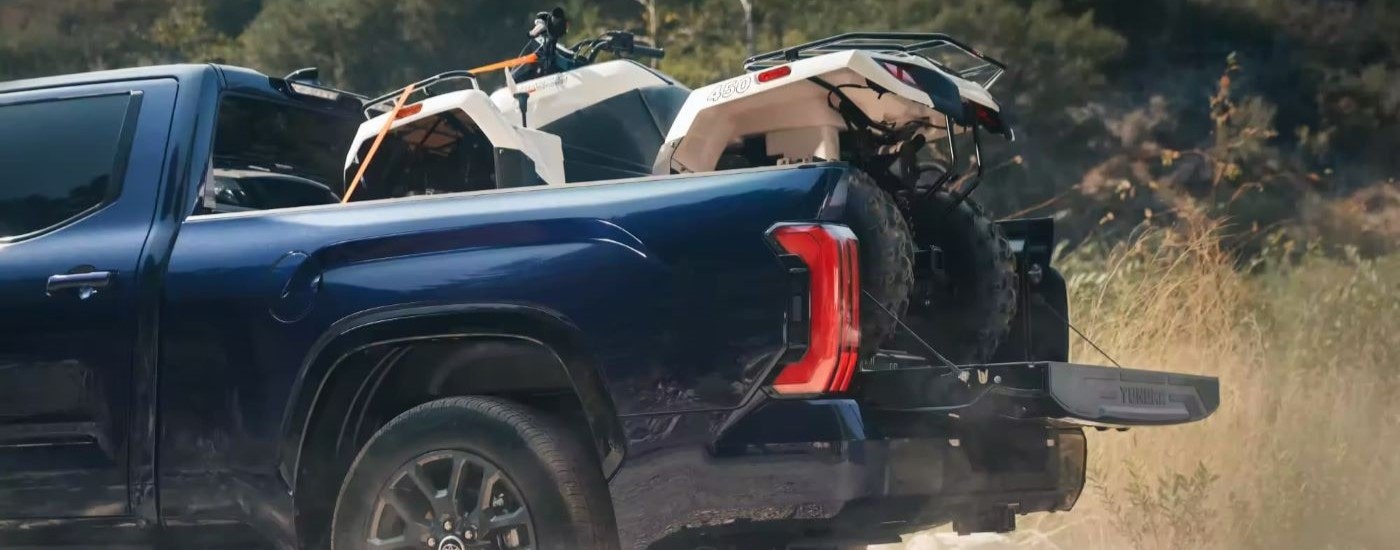 An ATV is shown in the bed of a blue 2023 Toyota Tundra Platinum.