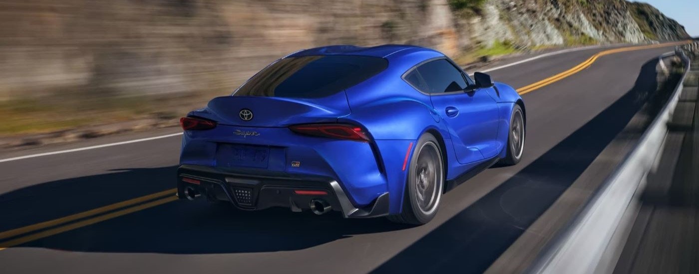 A blue 2023 Toyota GR Supra is shown driving on a mountain road.