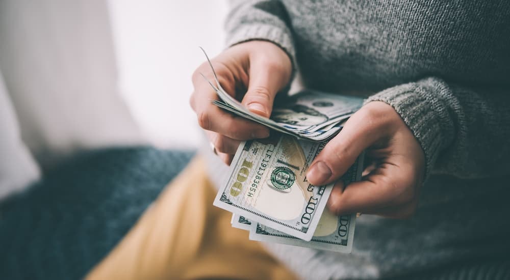 A close up shows a person holding cash.