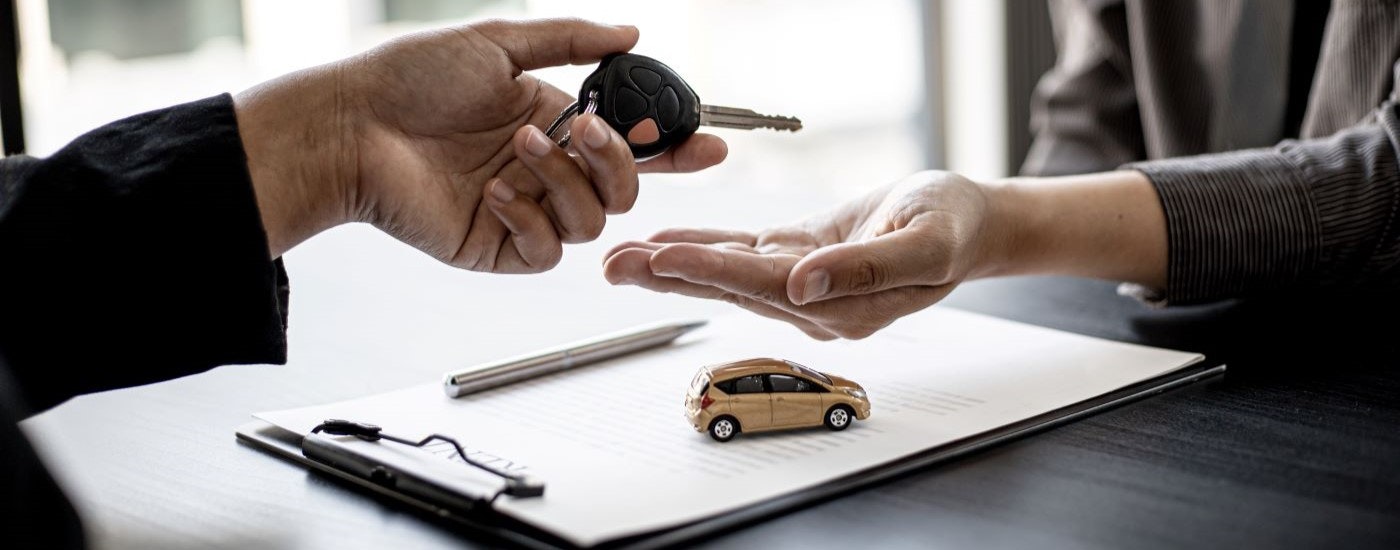 Two people are shown exchanging car keys.