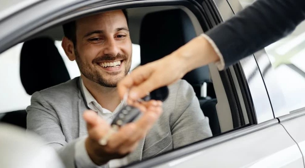 A smiling man is shown accepting a set of car keys.