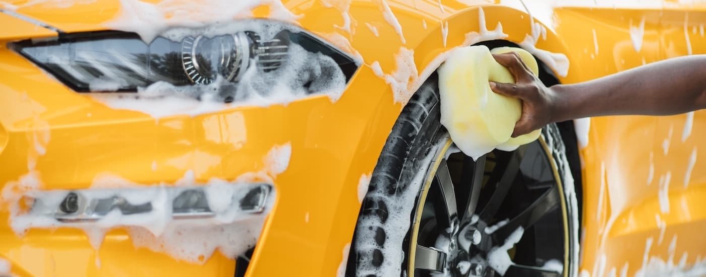 A close up shows a yellow 2021 Ford Mustang being washed.