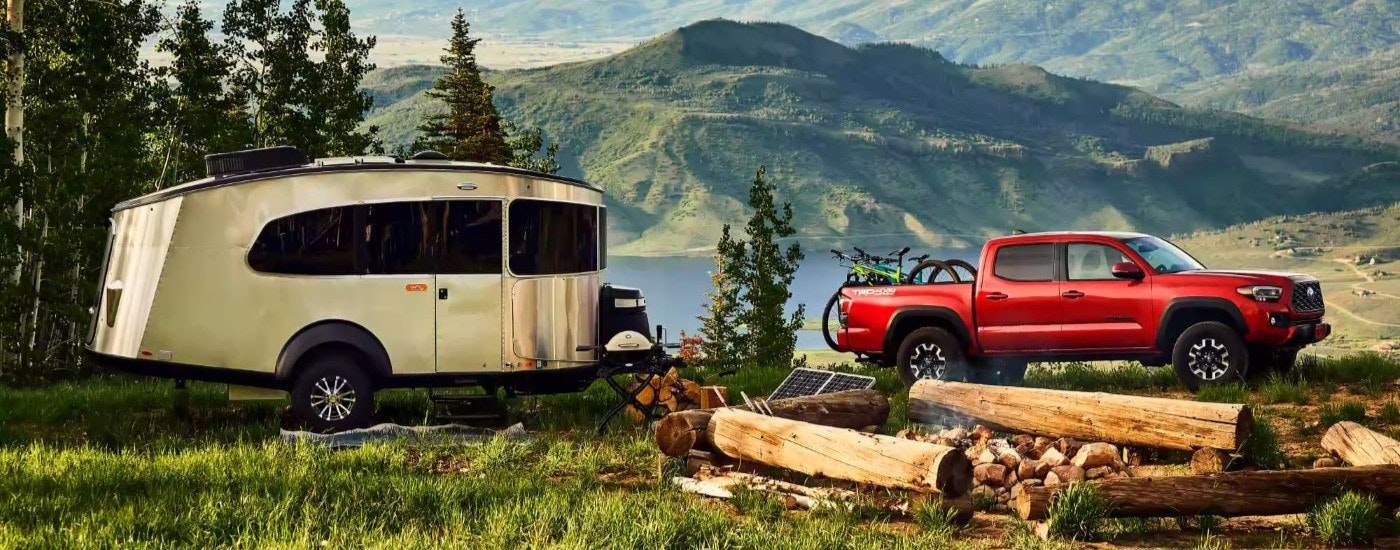 A red 2023 Toyota Tacoma TRD is shown at a campsite.