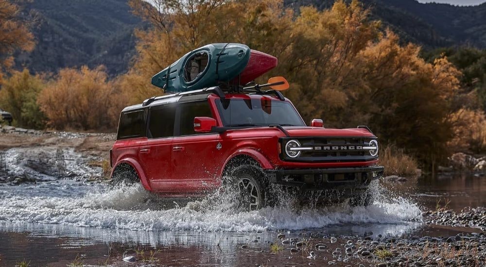 A red 2021 Ford Bronco Outer Banks is shown splashing through a creek.