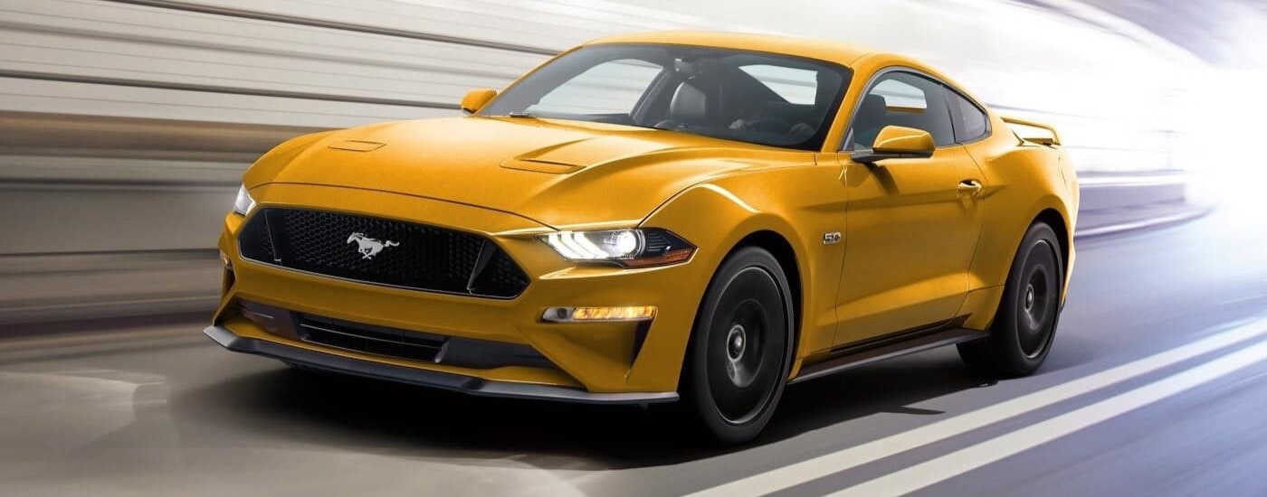 A yellow 2021 Ford Mustang GT is shown driving through a tunnel after leaving a used Ford dealer near Brattleboro, VT.