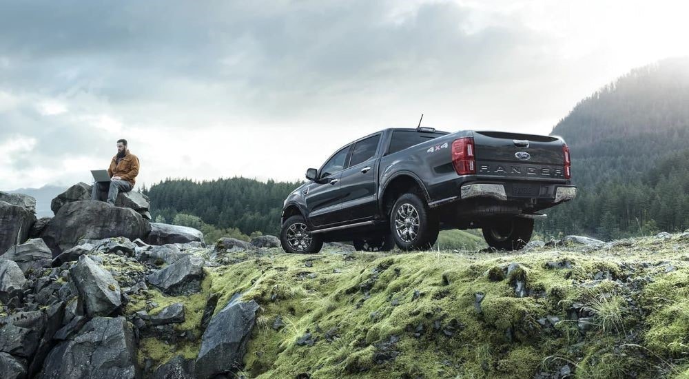 A person is shown using a laptop near a grey 2021 Ford Ranger Lariat.