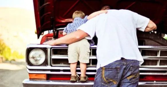 a father and son looking underneath a hood of a car