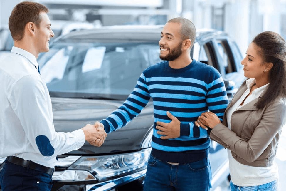 a couple shakes the hand of a sales men at a Toyota dealership