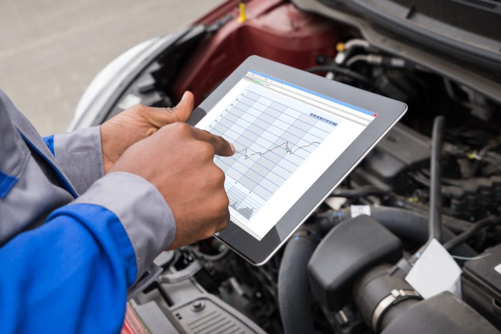 a person looking at a line graph on a tablet in front of a car