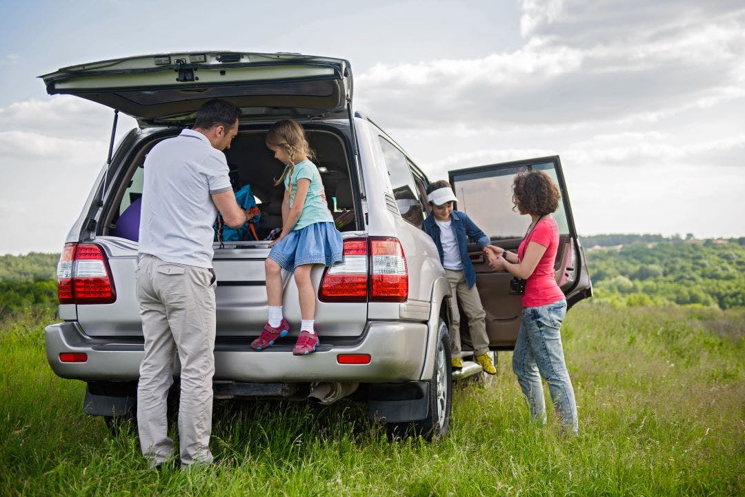 a family of four getting out of an SUV at a park