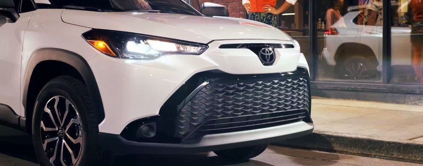 A close up shows the front end of a white 2023 Toyota Corolla Cross Hybrid S.