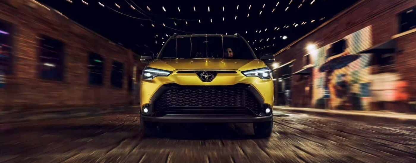 A yellow 2023 Toyota Corolla Cross Hybrid XSE is shown driving at night.