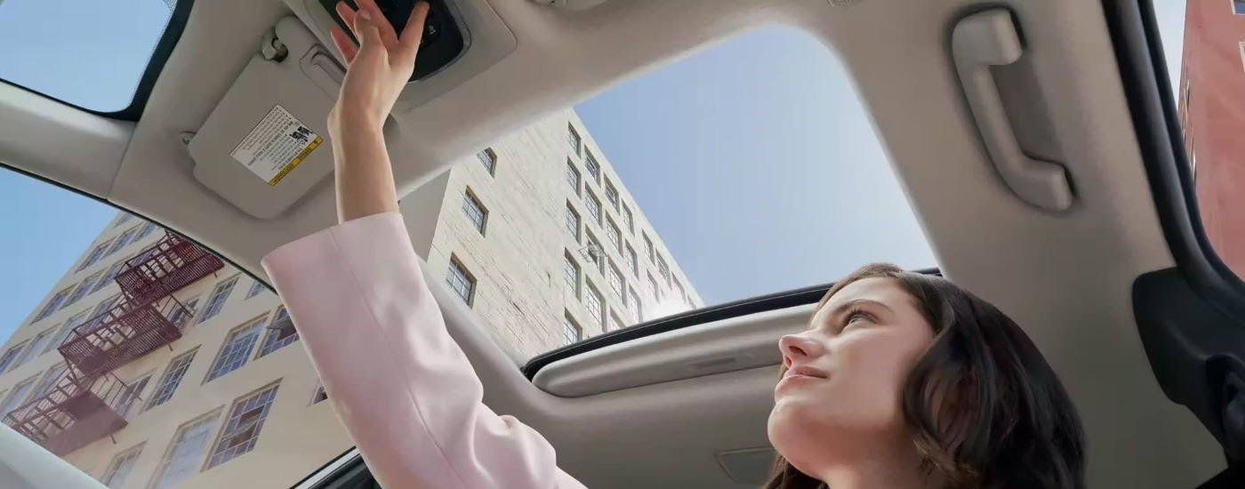 A person is shown opening the moonroof in a 2023 Toyota Corolla Cross.
