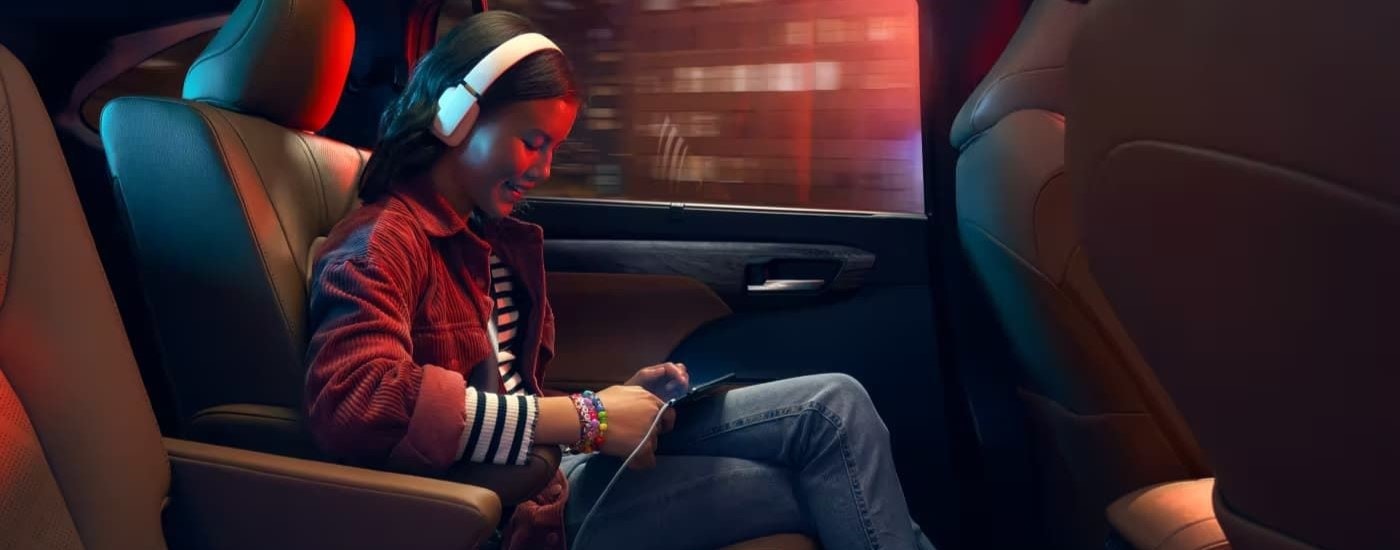 A person is shown listening to music in a 2023 Toyota Highlander.