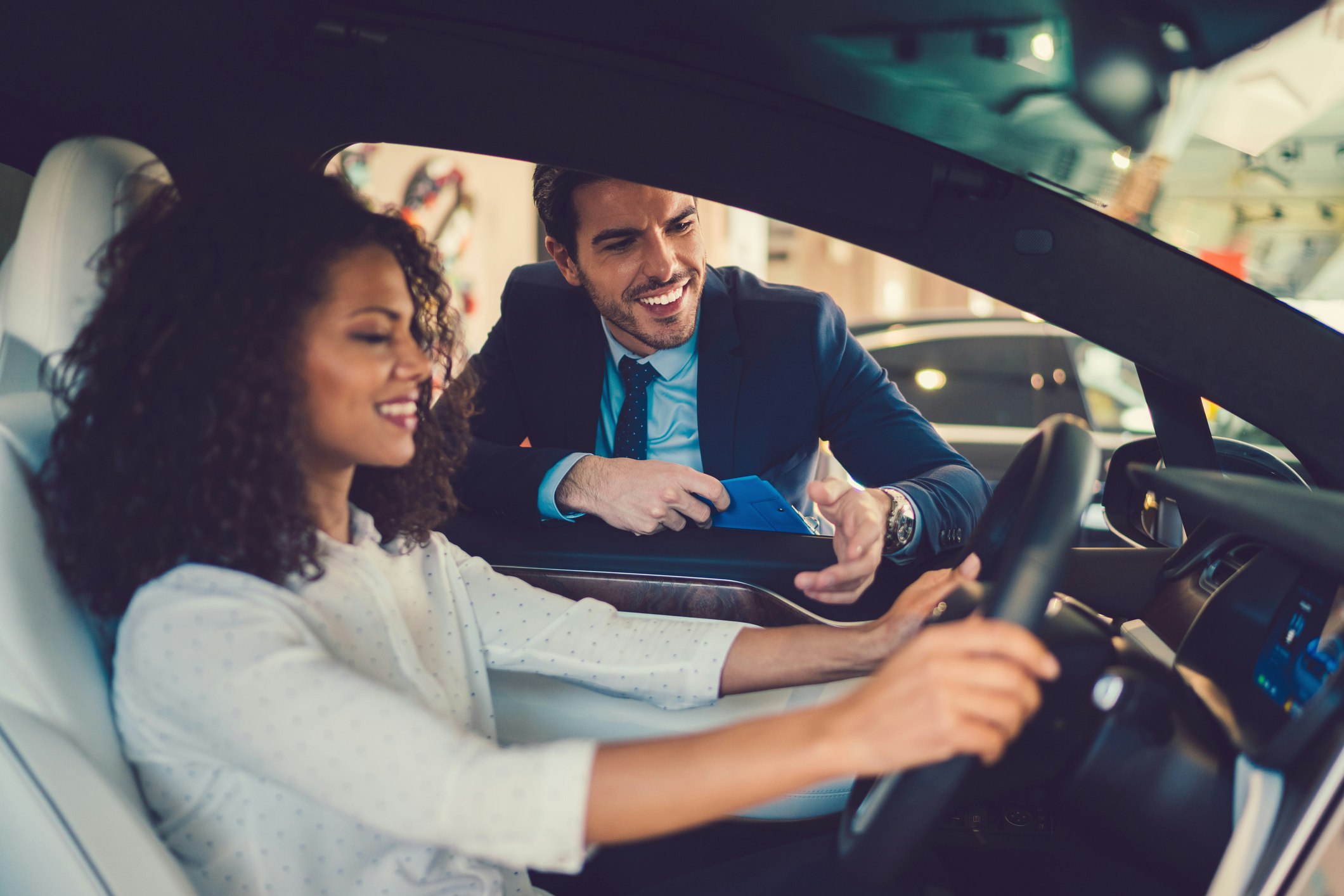 Woman and salesman looking at new car