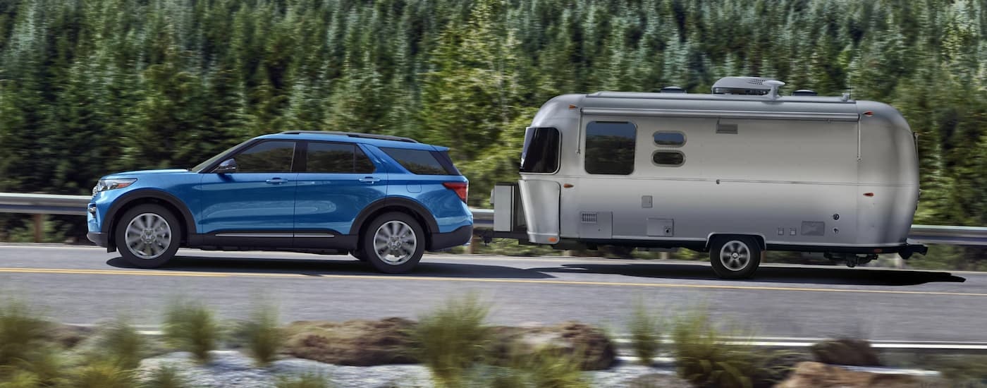 A blue 2021 Ford Explorer is shown from the side towing an Airstream trailer.