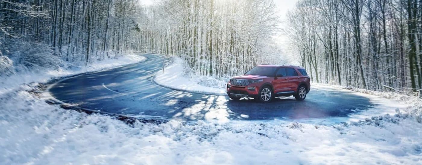 A red 2022 Ford Explorer for sale is shown rounding a snowy corner