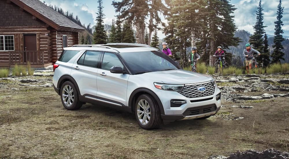 A white 2023 Ford Explore for sale is shown near a cabin.