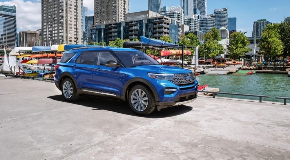 A blue 2023 Ford Explorer Limited is shown parked near kayaks and canoes.