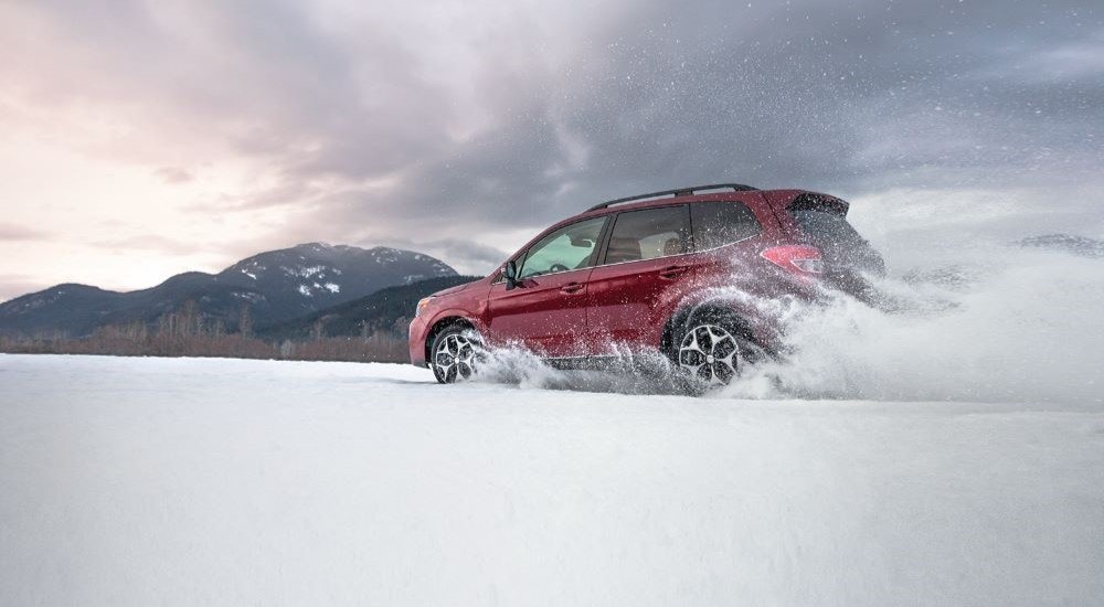A red 2016 Subaru Forester XT is shown kicking up snow after looking at a used Subaru SUV for sale.