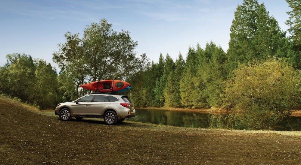 A silver 2016 Subaru Outback is shown next to a lake.