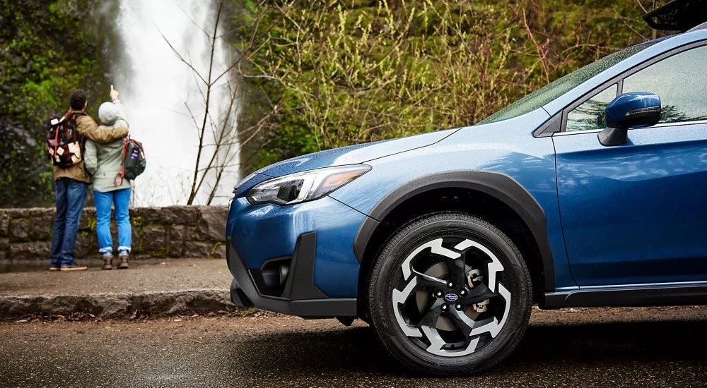 A blue 2022 Subaru Crosstrek Limited is shown near a waterfall.