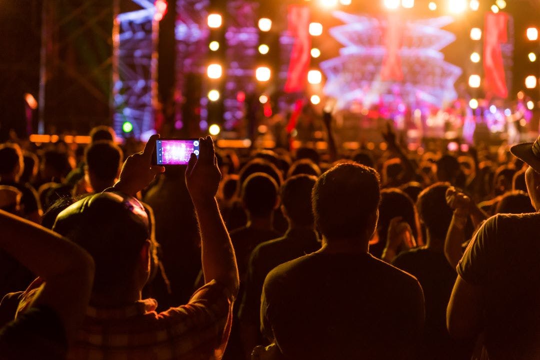 a person taking a photo at an outdoor concert
