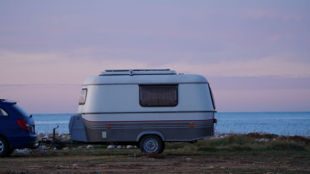 a car towing a camper near the water
