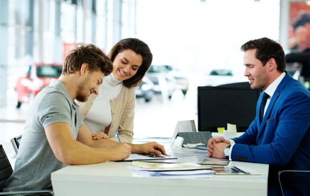 a person signing paperwork at a car dealership