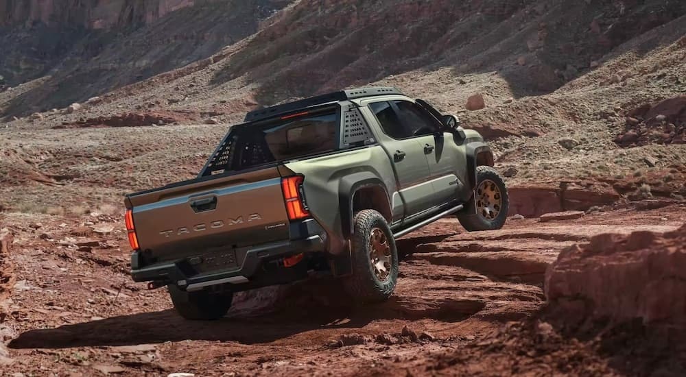 A green 2024 Toyota Tacoma TrailHunter is shown from the rear at an angle after leaving a dealer that has a Toyota Tacoma for sale.