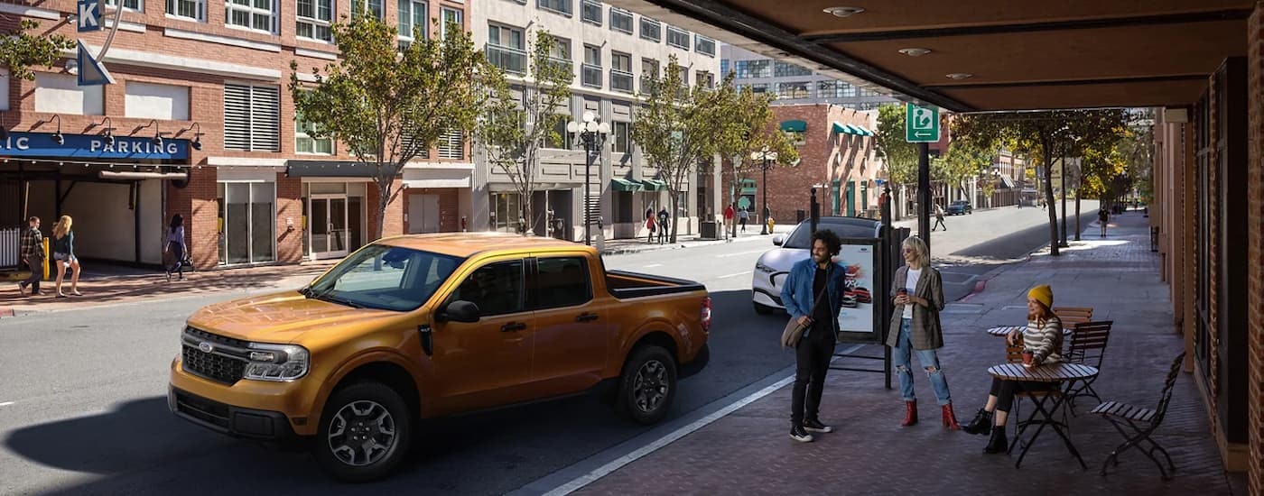 A gold 2022 Ford Maverick is shown from the side on a city street after leaving a Ford truck dealer.