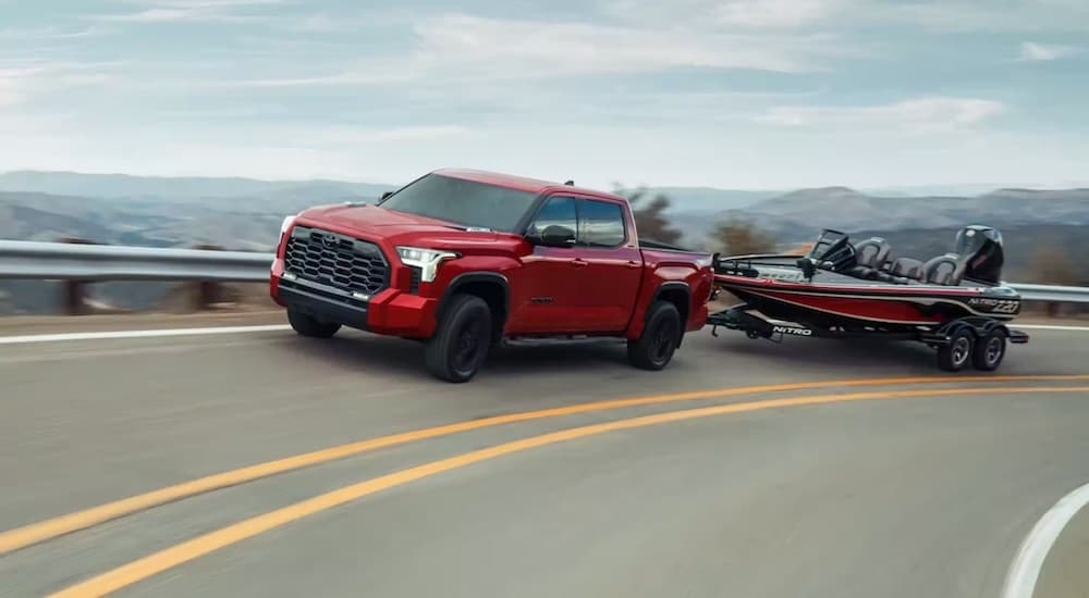 A red 2024 Toyota Tundra is shown from the side while towing a bass boat.
