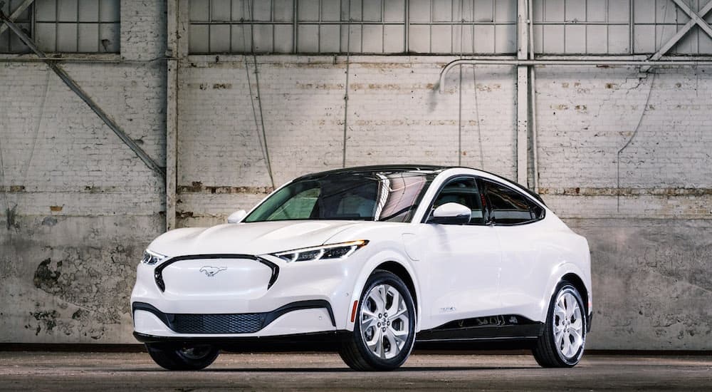 A white 2022 Ford Mustang Mach-E is shown from the front at an angle after leaving a dealer that has electric vehicles for sale.