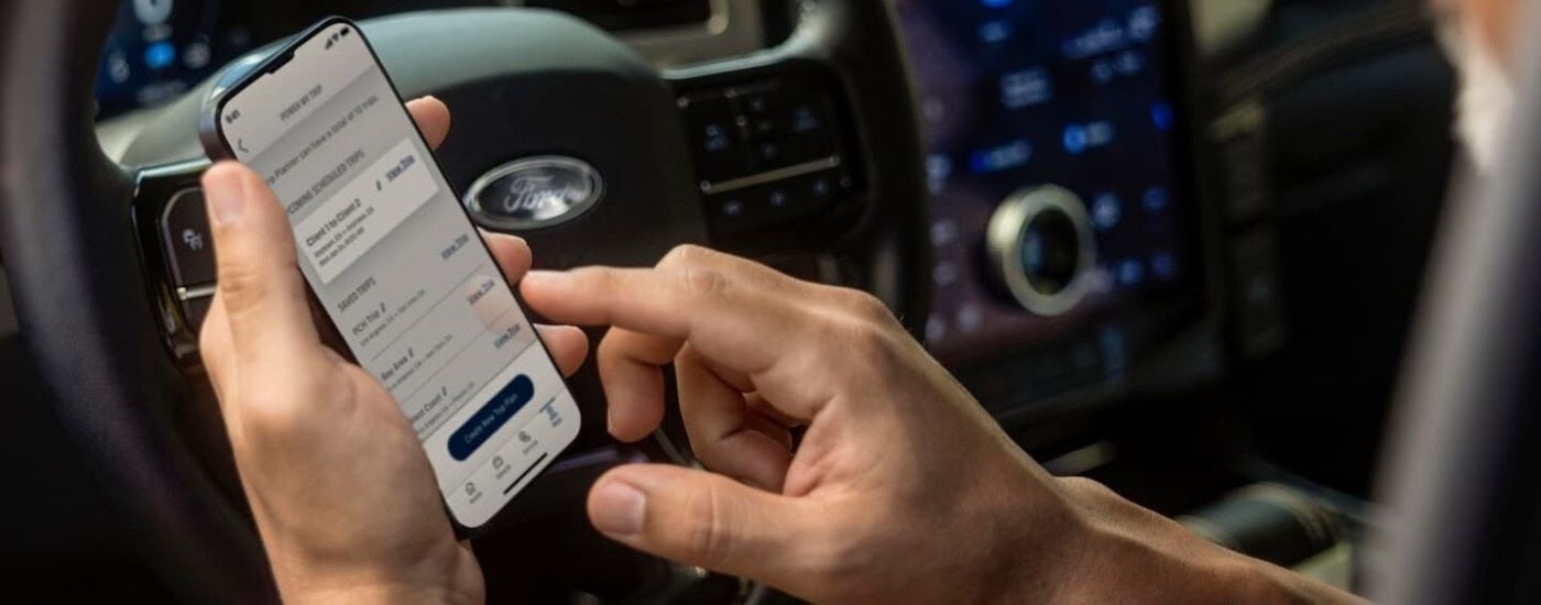 Someone is shown using a cellphone in a 2023 Ford F-150 Lightning.
