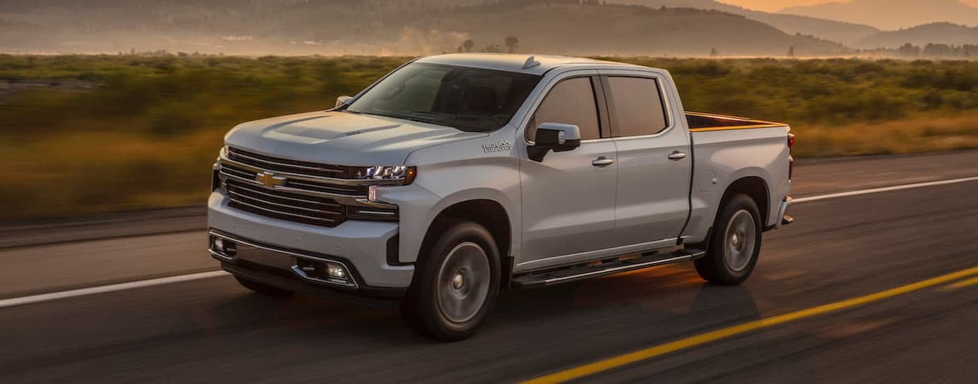 A blue 2019 Chevy Silverado 1500 is shown driving on an open road after viewing used Chevy trucks for sale.