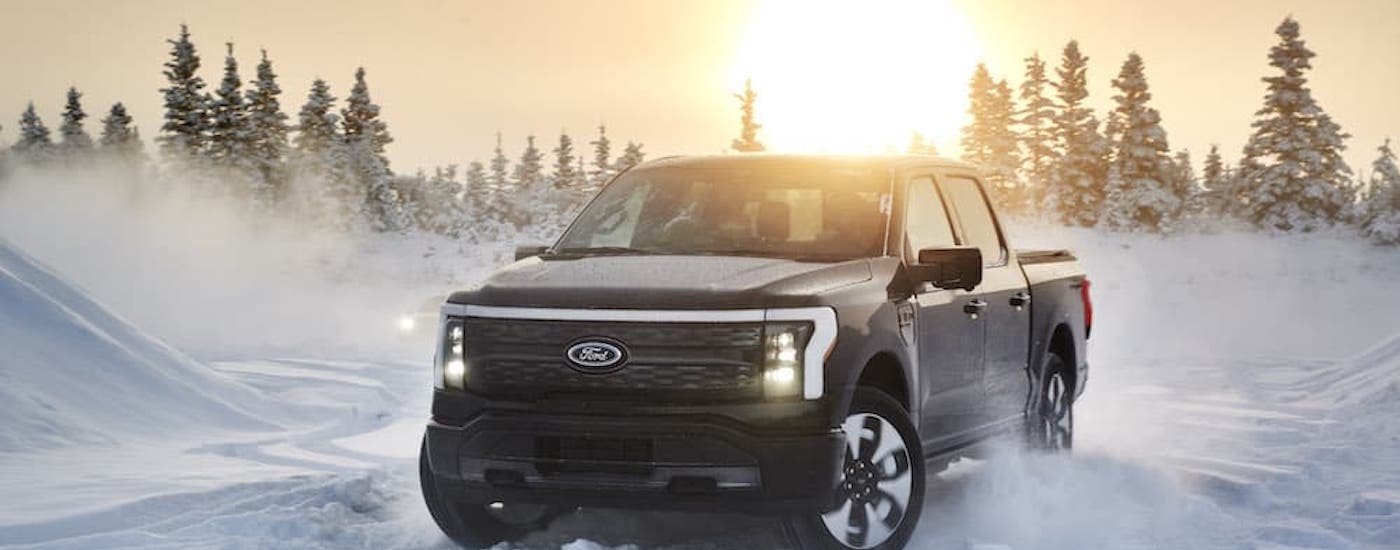 A black 2022 Ford F-150 Lighting is shown from the front at a angle in snow after leaving a Ford F-150 Lightning dealer.