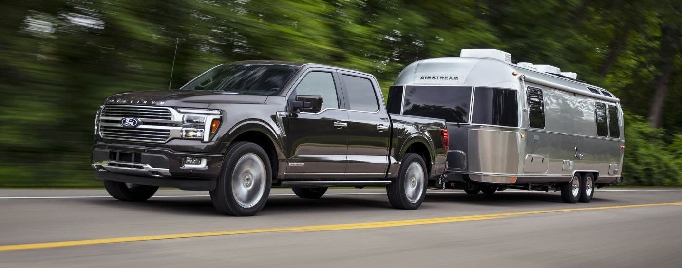 A black 2024 Ford F-150 Platinum is shown towing an airstream trailer.