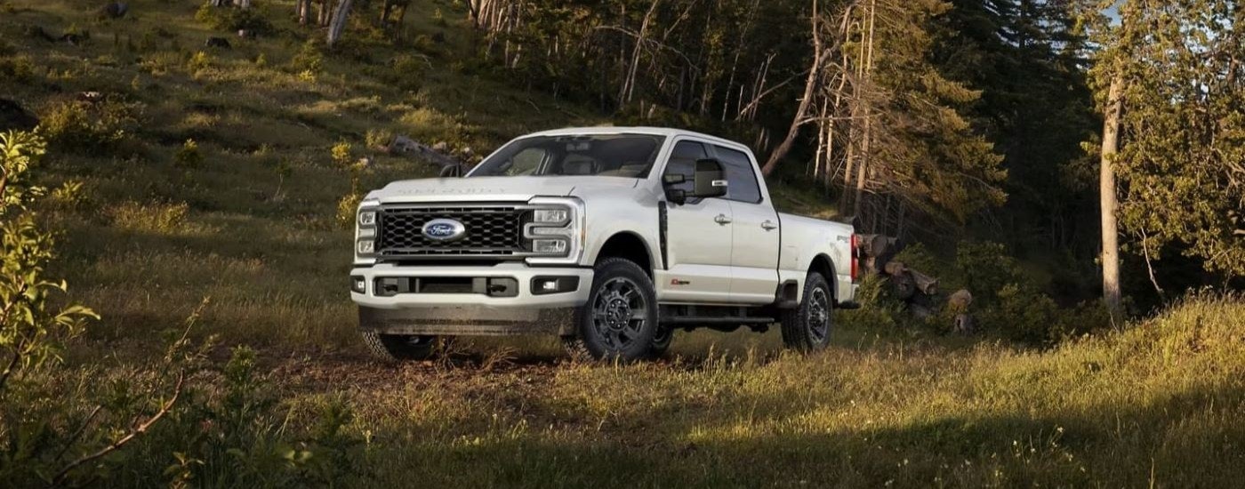 A white 2024 Ford Super Duty F-350 Lariat Sport is shown on a clearing in the woods.