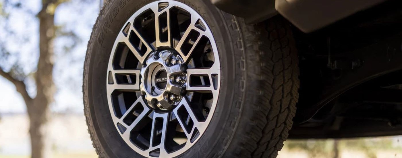 A close up shows the chrome wheel on black 2024 Ford Super Duty F-350 Limited.