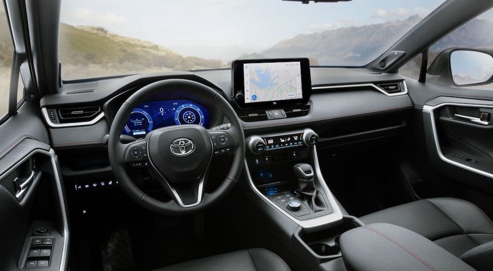 The black interior of a 2024 Toyota RAV4 Prime is shown from the driver's seat.
