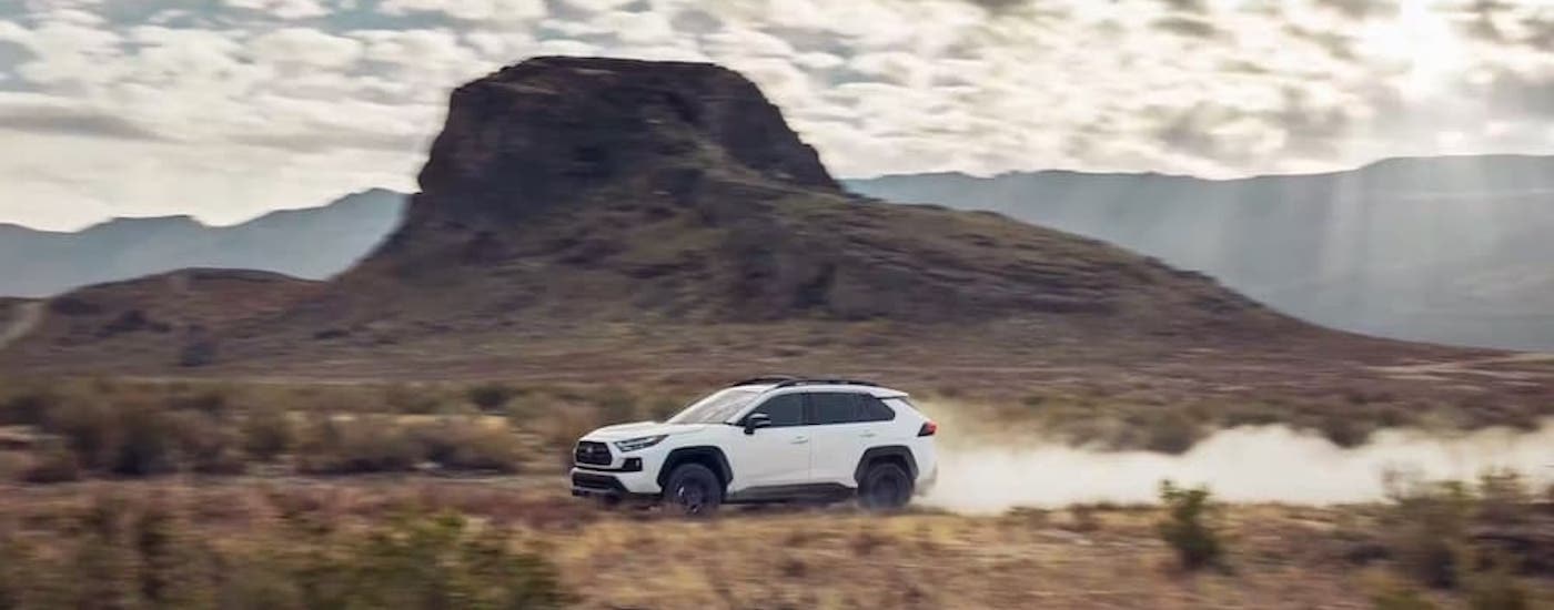 A white 2022 Toyota RAV4 is shown from the side while off-road.