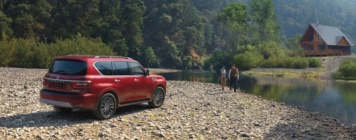 A red 2022 Nissan Armada is shown from the rear at an angle on a rocky shore.
