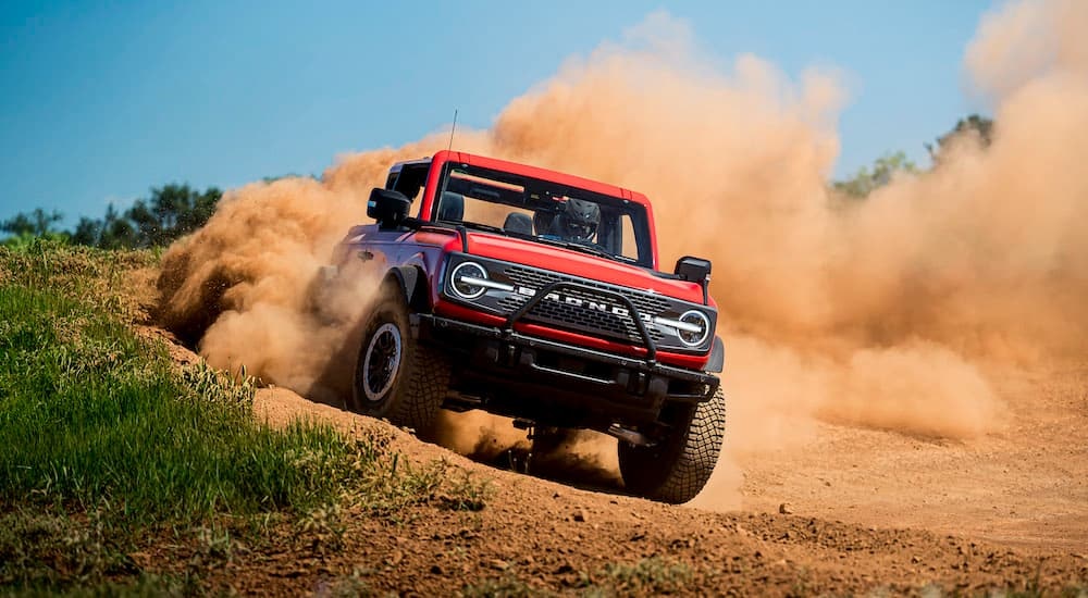 A red 2021 Ford Bronco Wildtrak is shown from the front while off-road after leaving a Ford Bronco dealer.