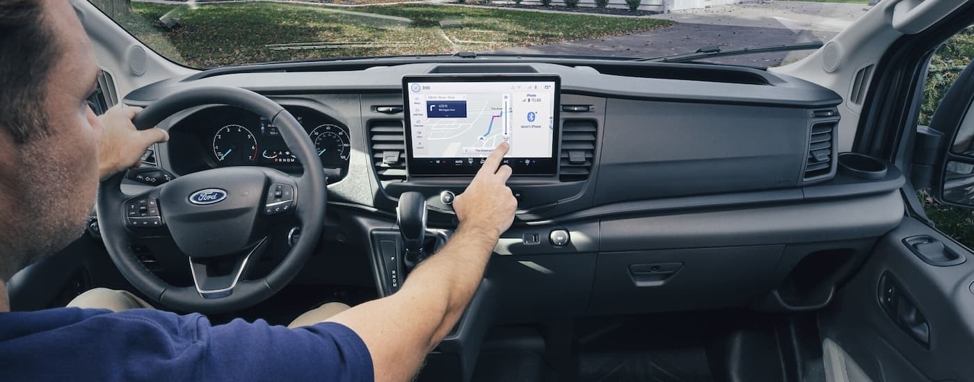 A driver is shown using the touch infotainment screen in a 2023 Ford Transit.